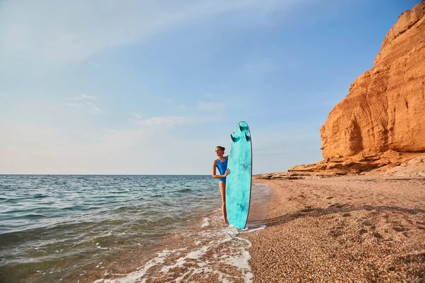 Пляж, приключения и концепция летнего отдыха. Симпатичная женщина с доской для серфинга на фоне природного ландшафта. Копирование пространства Стоковое Изображение