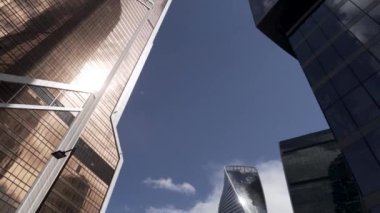 Mavi bulutlu gökyüzüne karşı iş bölgesinin cam gökdelenlerinin alt manzarası. Başla. Güzel ticari ofis binaları, modern mimari kavramı..