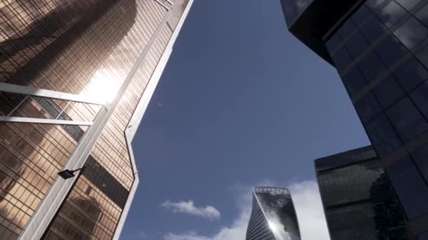 Bottom view of the glass skyscrapers of the business district against blue cloudy sky. Action. Beautiful commercial office buildings, concept of modern architecture. — Stock Video