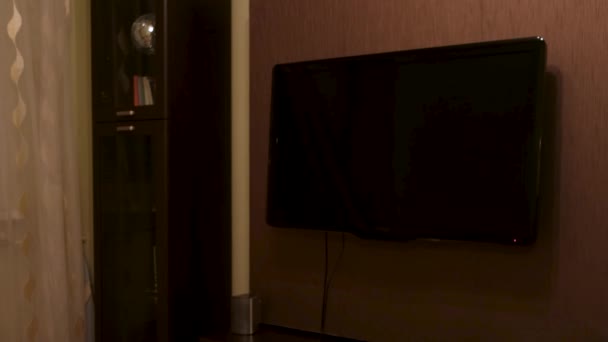 Детали интерьера гостиной с большим выключенным телевизором. Концепция. Телевизор с плоским экраном висит на коричневой стене рядом с узким деревянным секретарём. — стоковое видео