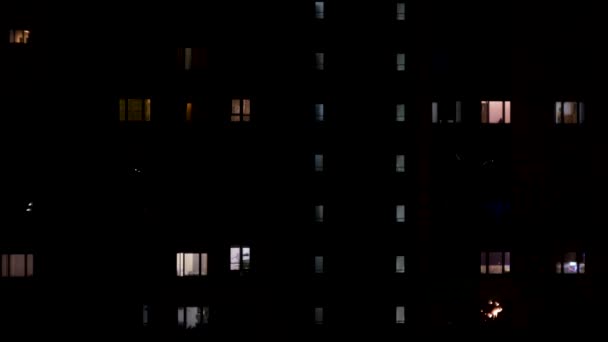 Noční pohled na světla v okně vícepodlažní budovy. Koncept. Vícepodlažní dům s apartmány pozdě večer, koncept nočního života. — Stock video