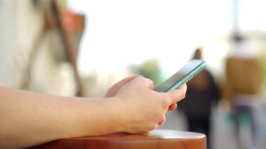 Şehrin bulanık arka planında yeni akıllı telefonu tutan kadınların yan görüntüsü. Medya. Elektronik modern aletini açık havada mesajlaşan ya da gezen bir kızın fotoğrafını çek..