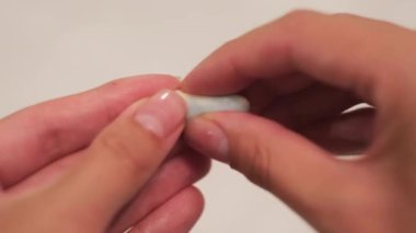 Beyaz arka planda kulak tıkacı tutan kadın. Kavram. Kadın ellerinin ses geçirmez kulak tıkaçlarını tutup parmaklarıyla bastırarak..