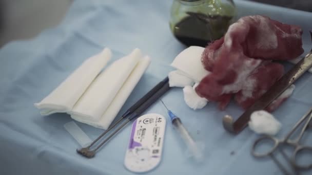 Krwawy bandaż na stole medycznym podczas operacji. Akcja. Zbliżenie narzędzi medycznych leżących na niebieskiej szacie na sali operacyjnej, pojęcie medycyny. — Wideo stockowe