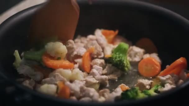 Koka en kyckling med grönsaker i en stekpanna. Begreppet. Närbild av omrörning och sjuder grönsaker och kött med en trä mat Turner, hälsosam kost. — Stockvideo
