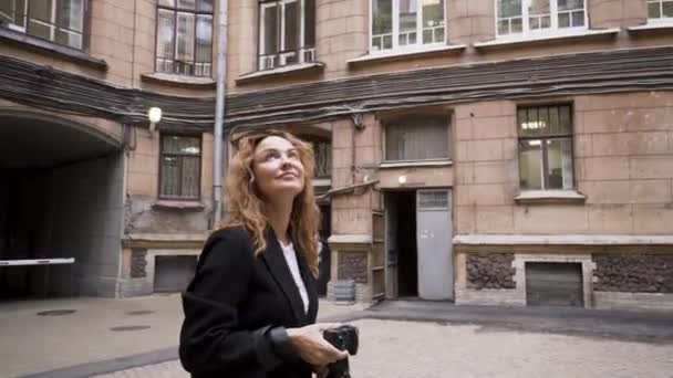 Belle femme se promène autour de la ville et prend des photos de l'architecture ancienne. L'action. Femme photographe prend des photos de l'architecture de la vieille ville. Femme marche dans les ruelles de la ville — Video