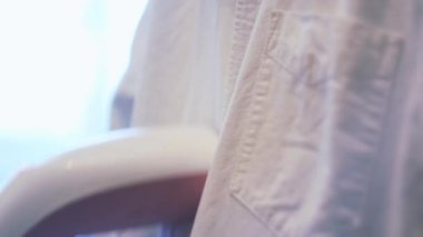 Giysileri ütülemek için manüel buharlı gemi kullanıyor. Kavram. Beyaz gömleği ütüleyen kadın ellerini kapat. Ev yapımı elektrikli fırça kullan..