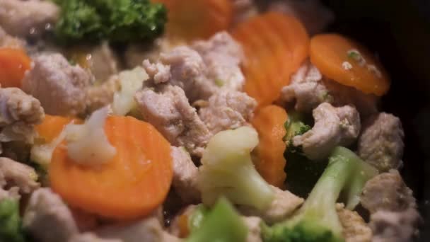 Sluiten van groenten in een pan wordt bereid met wit kippenvlees. Concept. Kook smakelijk diner van wortelen, broccoli, bloemkool, en stukjes kip. — Stockvideo