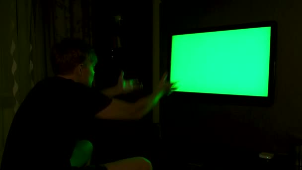 Widok z boku emocjonalnego mężczyzny oglądającego telewizję z zielonym ekranem w domu w nocy. Koncepcja. Mężczyzna patrząc zestresowany i rozczarowany podczas oglądania meczu sportowego w telewizji z klawiszem chroma. — Wideo stockowe