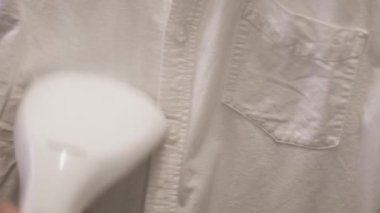 Buharlı gömleği düzeltiyorum. Kavram. Beyaz gömleğin ve kırışıklıkların üzerinden el yapımı buharlı tencerenin kapağı pürüzsüz. Buharlı gemiden hızlı cilt yumuşatma efekti