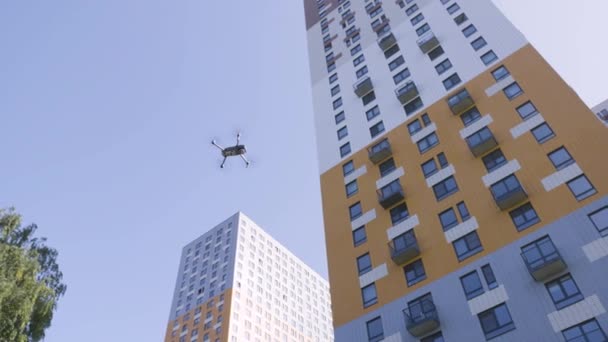Flying drone on background of house. Action. Bottom view of first flight of drone at multi-storey residential building. Drone flies on background of high-rise building on clear day — Stock Video