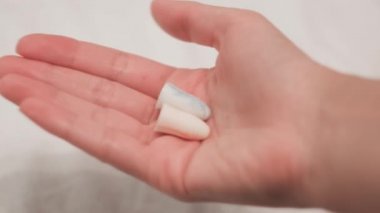 Kulaklar için kulak tıkaçları yakın plan. Kavram. Horlamak seni uyanık tutuyor, bu yüzden kadın kulak tıkacı takmanı öneriyor. İyi geceler uykusu için kulak tıkaçları.