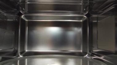 Mikrodalga fırının içine bak, yemek pişirme ve teknoloji kavramı. Ev gereçleri. Mikrodalga fırının içindeki boş mikrodalga pikabın tepsisini kapat..