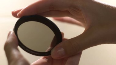 Kadın eli beyaz arka planda kamera merceği filtresi tutuyor. Kavram. Kadın ellerinin yuvarlak şekilli kamera filtresi açıp kapamasını kapat.