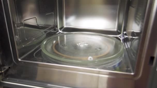 Rengör nya mikrovågsdetaljer. Husgeråd. Närbild på insidan av silver färg mikrovågsugn med rund formad glasbricka, matlagning maskin för hemmabruk. — Stockvideo