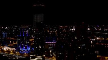 Iset gökdeleninin kara gökyüzü arka planında ışıklandırılmış havası. Stok görüntüleri. Milyonlarca ışık ve fenerle karanlık ve güzel şehrin üzerinde uçuyor..