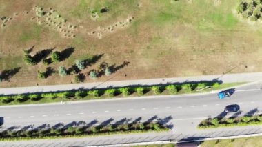 Yeşil çalılar ve kahverengi sonbahar çimenleri ile hareket eden arabaların bulunduğu bir yol manzarası. Şarjör. Yaz gezisi konsepti, güneşli bir günde araba sürmek..