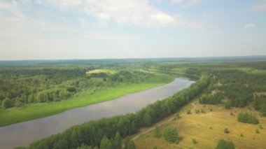 Güneşli bir günde sersemletici bir nehir ve sonbahar ormanı. Şarjör. Kırsal alan manzarası, yeşil ağaçlar, uzun kıvrımlı nehir ve bulutlu gökyüzü..