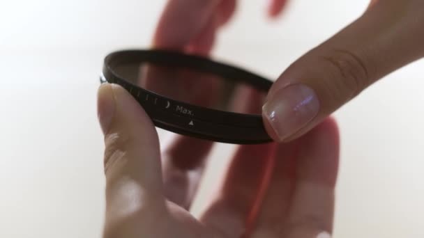 Close-up van polariserende lens filter in meisjes handen geïsoleerd op witte achtergrond. Concept. Vrouw die in het beide zijmechanisme van lensfilter verandert. — Stockvideo