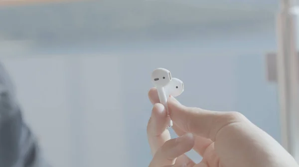 Close-up of wireless headphones in hands. Stock. Man passes pair of white wireless headphones. Stylish modern Bluetooth headphones — Stock Photo, Image