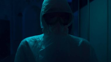 Korku araştırması detayları. Stok görüntüleri. Koruyucu takım elbiseli ve maskeli, korkunç bir şekilde koridorda yanıp sönen ışıkla dikilen bilinmeyen kişiye yaklaş..