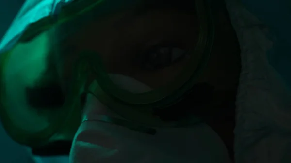 Details of a quest game in epidemic theme. Stock footage. Close up of a face of a manikin in a mask and protective suit in a dark room with dim light.