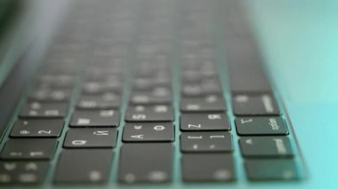 Laptopun yan görüntüsü ya da bilgisayar detayları, beyaz sembollü siyah klavye. Başla. Kamera odaklı arka planda ışıklandırılmış klavyenin aşırı yakınlaşması.