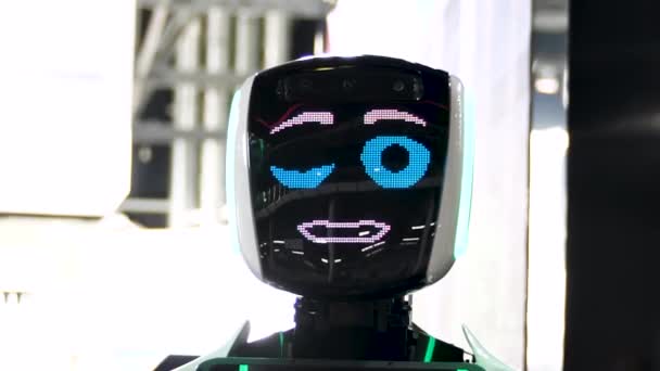 Robot divertente con grandi occhi azzurri sorridenti, parlanti e ammiccanti. Meida. Primo piano dello schermo facciale del robot con un sorriso amichevole all'esposizione delle tecnologie moderne. — Video Stock