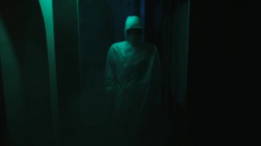 Kamera, maske ve tulum giymiş bir mankenden yavaşça uzaklaşıyor. Stok görüntüleri. Yanıp sönen ışıkla kasvetli koridor, psikolojik korku filmi sahnesi.