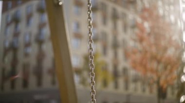 Güneş ışığının arka planındaki salıncak zincirinin yakın çekimi. Başla. Güneşli sonbahar gününün bulanık arka planında güzel salıncaklar zinciri