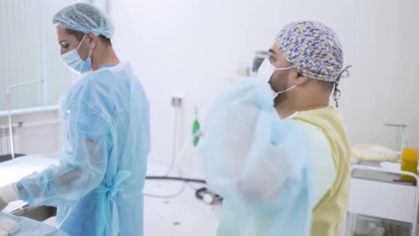 Os cirurgiões preparam-se para a cirurgia. Acção. Os cirurgiões se vestem antes da cirurgia e se preparam. Cirurgião coloca em vestido de vestir descartável estéril para cirurgia — Vídeo de Stock