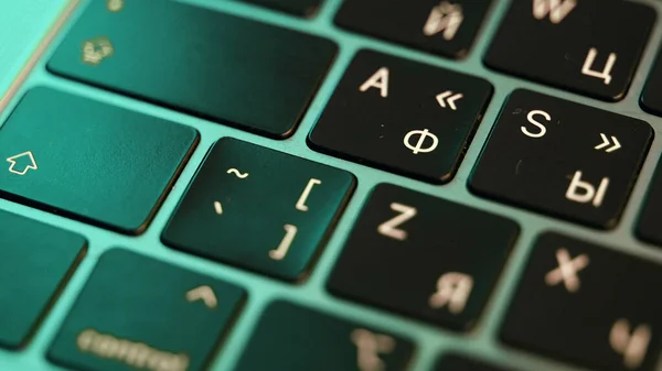 Zamknij laptopa lub klawiaturę komputera. Akcja. Koncepcja nowoczesnych urządzeń i technologii, przyciski czarnej klawiatury pod zielonym światłem. — Zdjęcie stockowe