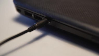 Erkek eli bilgisayar ya da laptop portundan kulaklık kablosunu çıkartırken yakın çekim. Medya. Kabloyu beyaz arkaplanda izole edilmiş aygıttan ayırıyorum.