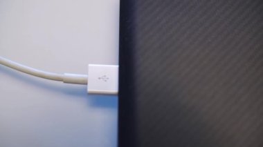 Beyaz USB kabloyla şarj etme işlemi. Medya. Erkek ellerinin bir dizüstü bilgisayar ya da USB konnektöründen beyaz USB kablosunu çıkarmasını kapat.
