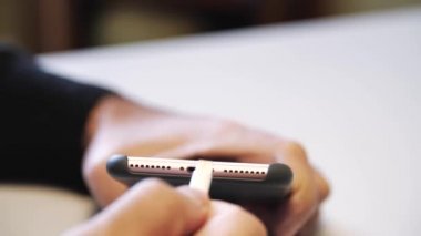 Cep telefonuna USB kablo şarj cihazı yerleştirmek. Medya. Adam elini kapatır ve yıldırım kablosuyla akıllı bir telefona şarj cihazı yerleştirir..