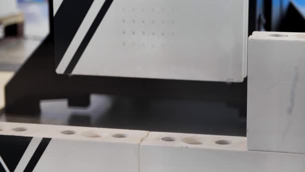 Industrirobotmaskin på den internasjonale industriutstillingen. Mediene. Tett inntil en robot som setter en hvit murstein i et vegglag, teknologier for bybyggeplass. – stockvideo