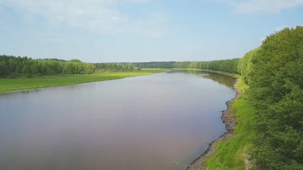 Luftaufnahme eines breiten Flusses zwischen grünen Bäumen, glatte Biegung des Kanals. Clip. Wald am Ufer des Stausees, Sommerlandschaft auf blauem bewölkten Himmel Hintergrund. — Stockfoto