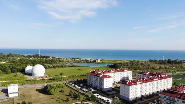 Kleine mediterrane Stadt direkt am Meer. Clip. Panorama-Luftaufnahme einer schönen grünen Stadt und das Meer auf blauem bewölkten Himmel Hintergrund. — Stockfoto