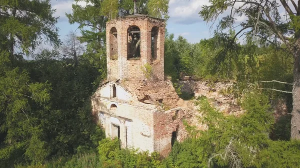 Iglesia abandonada en el bosque. Clip. Vista aérea de la antigua iglesia con un campanario y una cúpula en ruinas en el fondo de árboles verdes en colores brillantes y soleados. —  Fotos de Stock