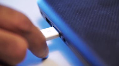 Beyaz USB kabloyla şarj etme işlemi. Medya. Erkek ellerinin bir dizüstü bilgisayar ya da USB konnektöründen beyaz USB kablosunu çıkarmasını kapat.