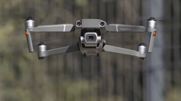 Drone met een camera zweeft in de lucht. Actie. Close-up van een vliegtuig en bladen die draaien in slow motion op wazige achtergrond van groene bomen, schieten proces. — Stockfoto