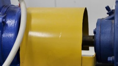 Motorun mavi ve sarı renkte dönen elementini kapat. Medya. Ağır sanayi konsepti olan endüstriyel fabrikada metal üretimi ve üretimi.