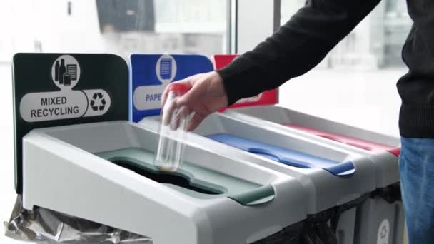 Sluiten van prullenbakken van verschillende kleuren voor het recyclen van verschillende materialen. De media. Man hand gooien plastic lege fles in de prullenbak, concept van ecologie, afvalscheiding punt voor plastic — Stockvideo