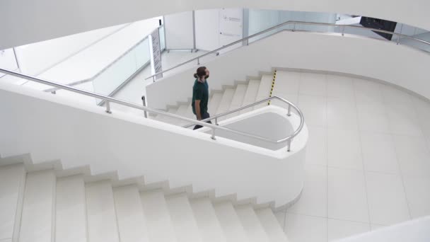 Vista interior de un edificio moderno con hombres caminando por la escalera. Medios. Hermosas escaleras completamente blancas de un centro de negocios, concepto de minimalismo en arquitectura. — Vídeo de stock