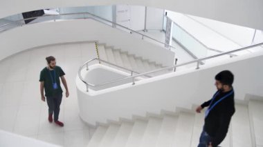 Kapalı alanda, merdivenlerde yürüyen adamların olduğu modern bir bina. Medya. Mimaride minimalizm kavramı bir iş merkezinin tamamen beyaz merdivenleri..