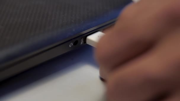 Inserimento a mano cavo USB bianco nel computer portatile isolato su sfondo bianco. I media. Primo piano del dispositivo di collegamento a un computer con un cavo. — Video Stock