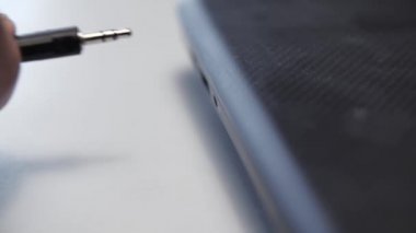 Kulaklık kablosu dizüstü bilgisayara yerleştirildi. Medya. Adamın kulaklık konnektörüyle dizüstü bilgisayara kablo yerleştirdiği yakın plan. Kulaklıklar kabloyla dizüstü bilgisayara bağlanıyor