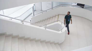 Kapalı alanda, merdivenlerde yürüyen adamların olduğu modern bir bina. Medya. Mimaride minimalizm kavramı bir iş merkezinin tamamen beyaz merdivenleri..