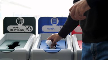 Çevre ve ekoloji kavramı. Medya. Makarna kutusu ve makbuzu kağıt atmak için kullanılan çöp kutusuna atan adamlara yakın çekim..