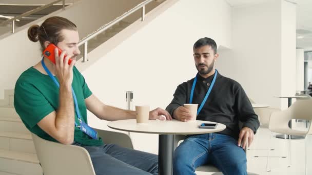 Los trabajadores se sientan a almorzar en la cafetería. Medios. Dos trabajadores con placas están sentados en la mesa. Los trabajadores de oficina se relajan en su hora de almuerzo — Vídeos de Stock